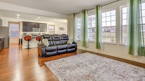 A spacious living room with a leather sofa, a coffee table, and a large rug. There is a kitchen area with cabinets and a microwave in the background. - Centrally Located Home in Fredericksburg! (Fredericksburg)