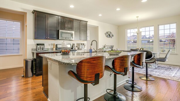 A kitchen with dark cabinets, a granite countertop, and a central island with bar stools. - Centrally Located Home in Fredericksburg! (Fredericksburg)