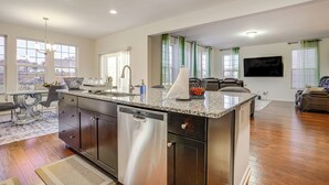 A modern kitchen with a dishwasher, granite countertop, and a dining area with a table and chairs. - Centrally Located Home in Fredericksburg! (Fredericksburg)