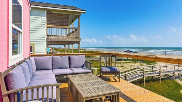 Een pand aan het strand met balkon, een bank en een tafel.