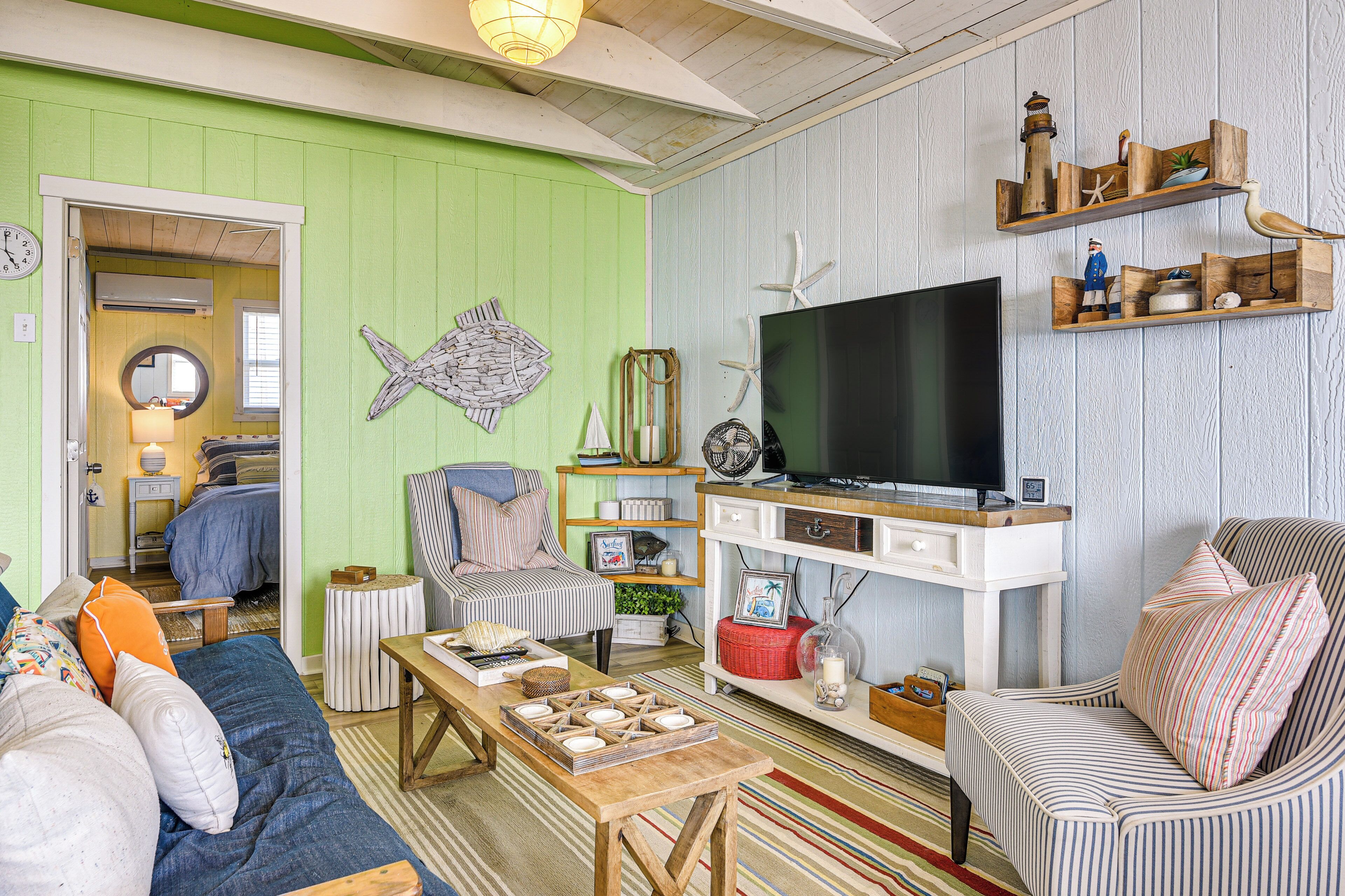 A cozy living room with a television, striped furniture, and a fish wall decoration.