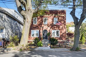 Una casa a due piani in mattoni con un ingresso principale, delle scale e una piccola bandiera americana.