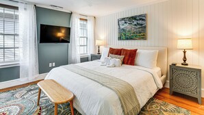 A bedroom with a bed, a TV, a painting, and a patterned rug. - Walk to Constitution Beach: Mid-century Boston Gem (Boston)