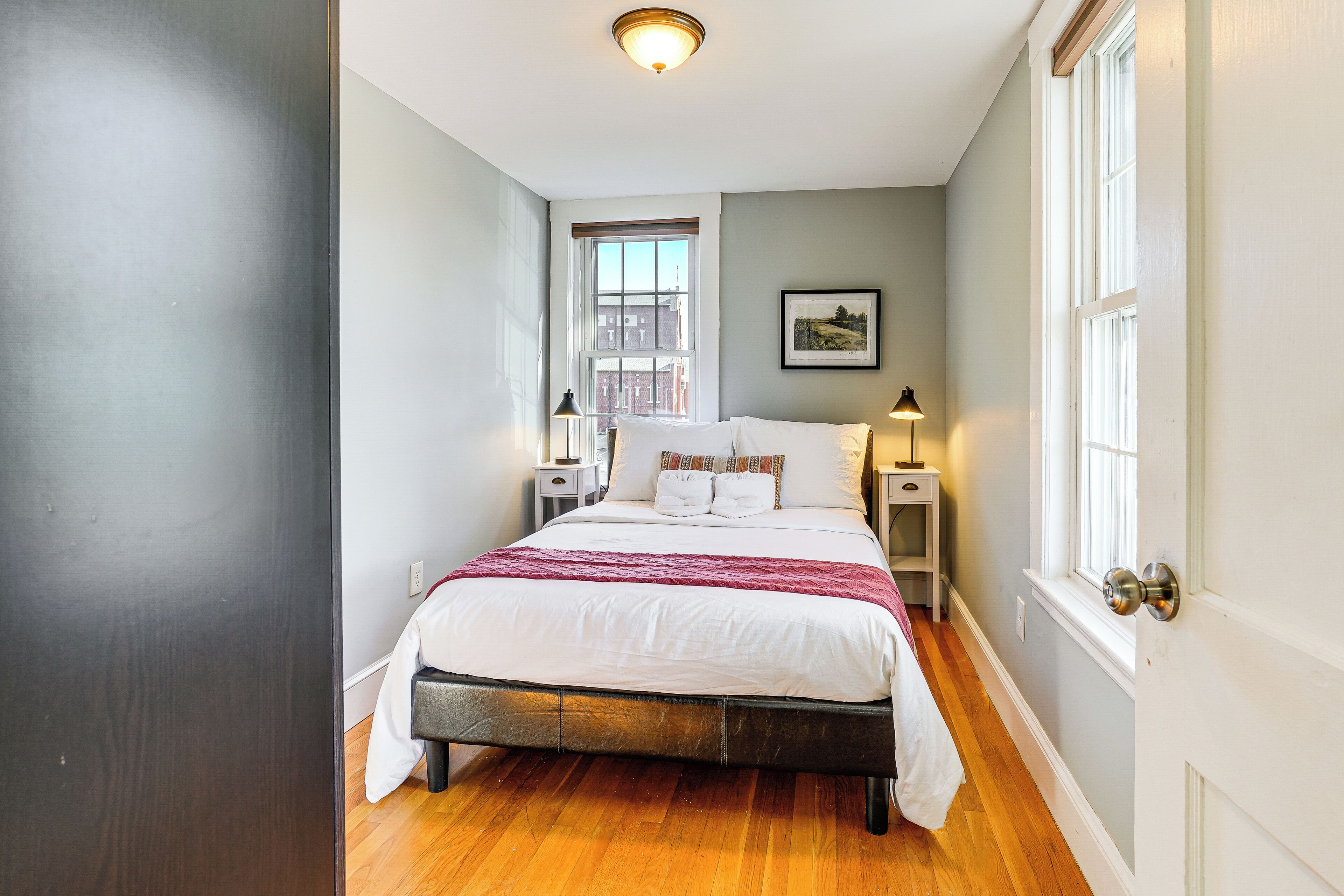 Une chambre à coucher avec un lit, des tables de chevet, une fenêtre et une porte.