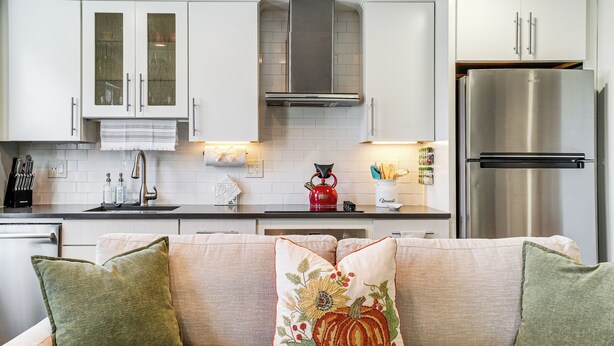A modern kitchen with white cabinets, a stainless steel refrigerator, and a countertop with various kitchen items. - Walk to Constitution Beach: Mid-century Boston Gem (Boston)