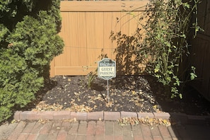 A sign indicating guest parking in a landscaped area with a wooden fence and foliage. - Walk to Constitution Beach: Mid-century Boston Gem (Boston)