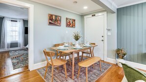 A dining area with a wooden table set for six, surrounded by chairs, with a patterned rug on the floor. - Walk to Constitution Beach: Mid-century Boston Gem (Boston)