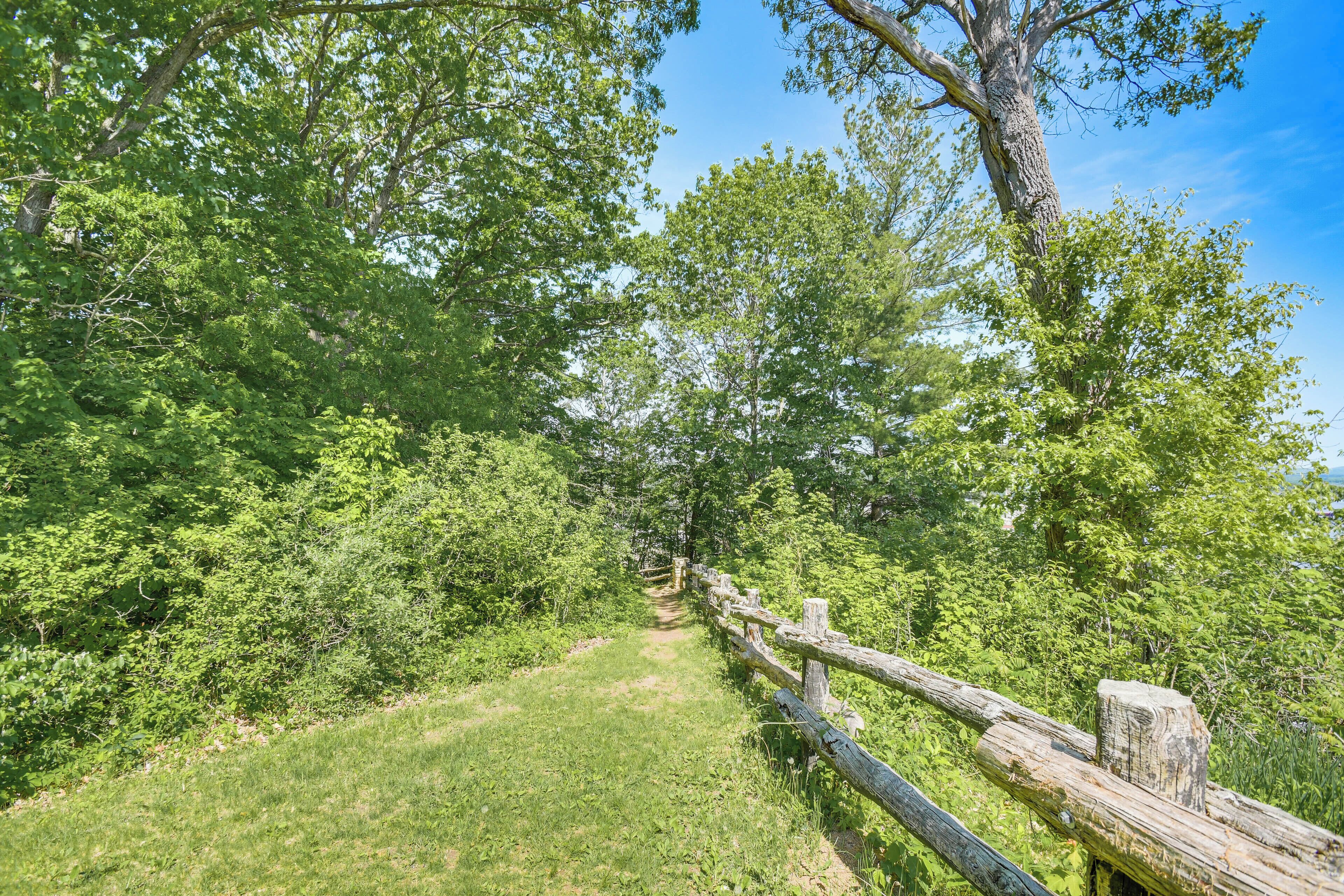 A forested hiking trail with a wooden fence.