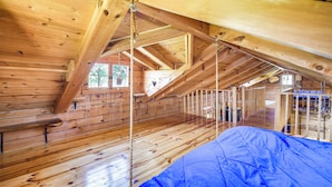 A wooden cabin with a loft bedroom, a wooden floor, and a blue tarp on the floor. - Bellevue Log Cabin w/ Gas Grill & Creek Access (Bellevue)