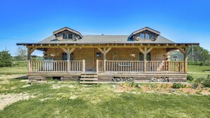 A log cabin with a covered porch, stone foundation, and a grassy yard. - Bellevue Log Cabin w/ Gas Grill & Creek Access (Bellevue)