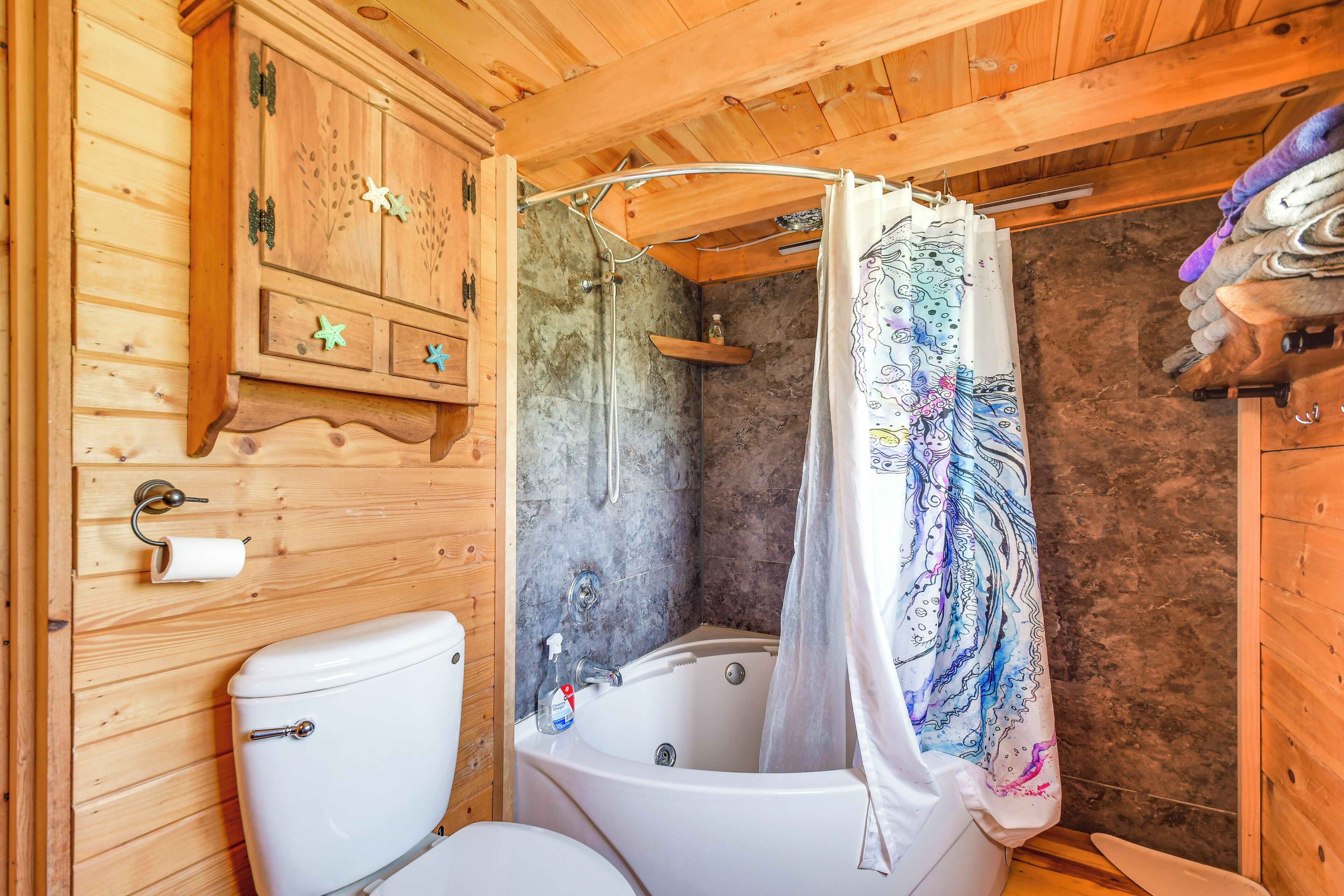 A wooden cabin bathroom with a toilet, bathtub, and shower.