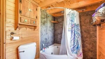 A wooden cabin bathroom with a toilet, bathtub, and shower.