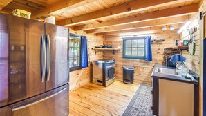 A compact kitchen with a stainless steel refrigerator, a built-in oven, and a sink. - Bellevue Log Cabin w/ Gas Grill & Creek Access (Bellevue)