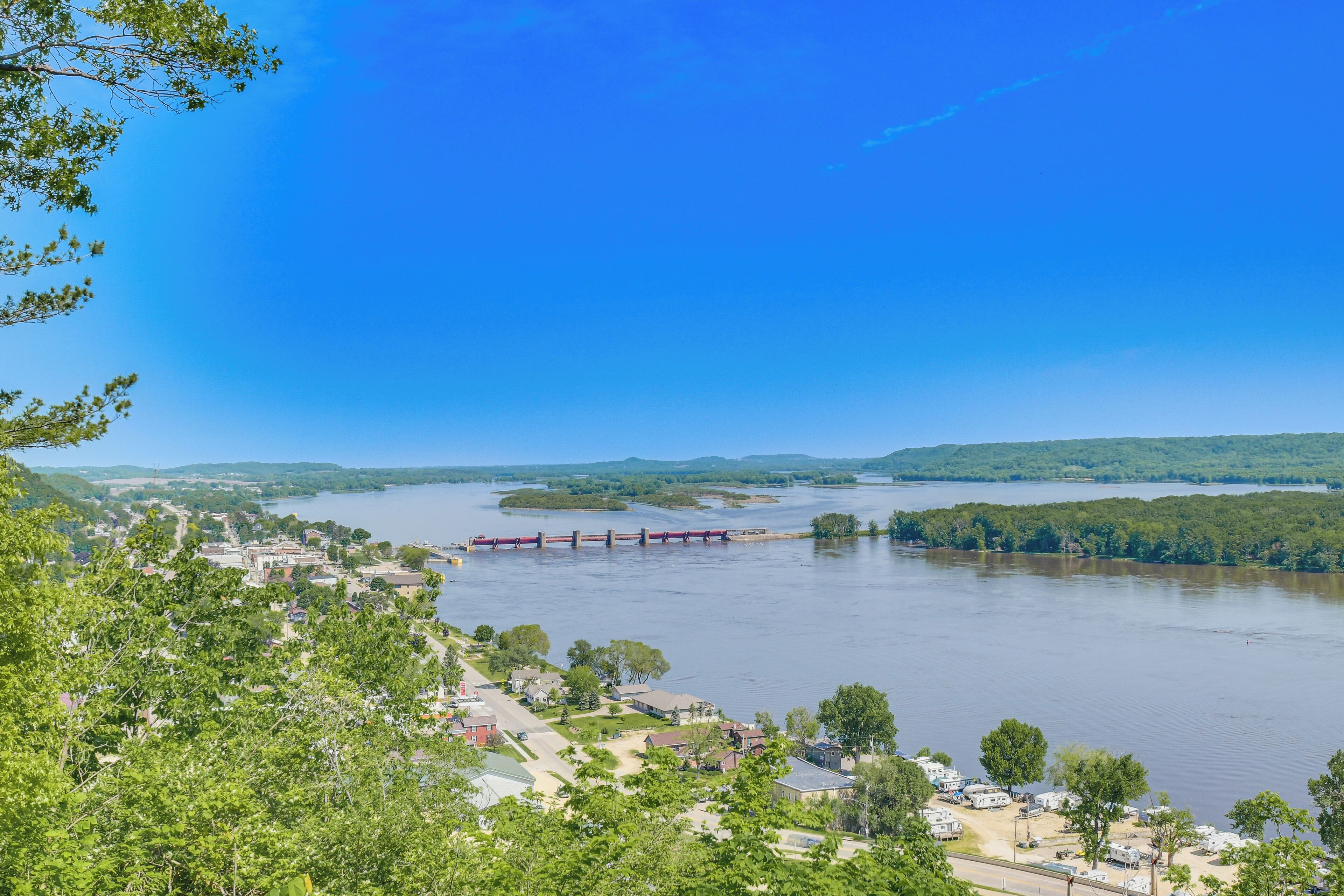 A river with a bridge, surrounded by greenery and a small town.