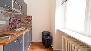 A compact kitchen with a microwave, sink, and two trash bins. - Apartments in the heart of Berlin  (Berlin)