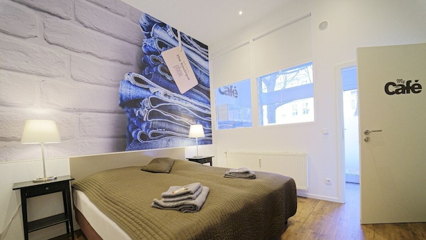 A bedroom with a large bed, two bedside tables, a wall with a denim jeans artwork, and a door labeled "My Café". - Apartments in the heart of Berlin  (Berlin)