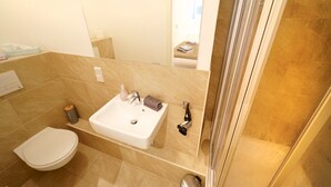 A bathroom with a white sink, a toilet, and a shower area. - Apartments in the heart of Berlin  (Berlin)