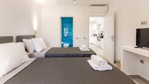 Une chambre d’hôtel avec deux lits, une télévision et une salle de bain visible à travers une porte bleue.