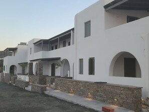 A modern building with white walls, stone accents, and arched doorways.