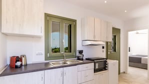 Uma cozinha moderna com ilha central, armários embutidos, janela com vista e micro-ondas.