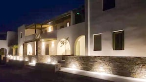 A modern building with a stone facade, arched windows, and a well-lit entrance. - Ampelas Nostalgia Gem - Seaview Getaway in Paros (Paros)