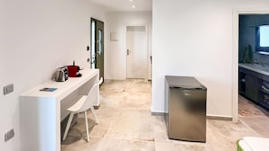 A modern kitchen with a white countertop, a stainless steel refrigerator, and a small seating area with a white chair. - Ampelas Nostalgia Gem - Seaview Getaway in Paros (Paros)