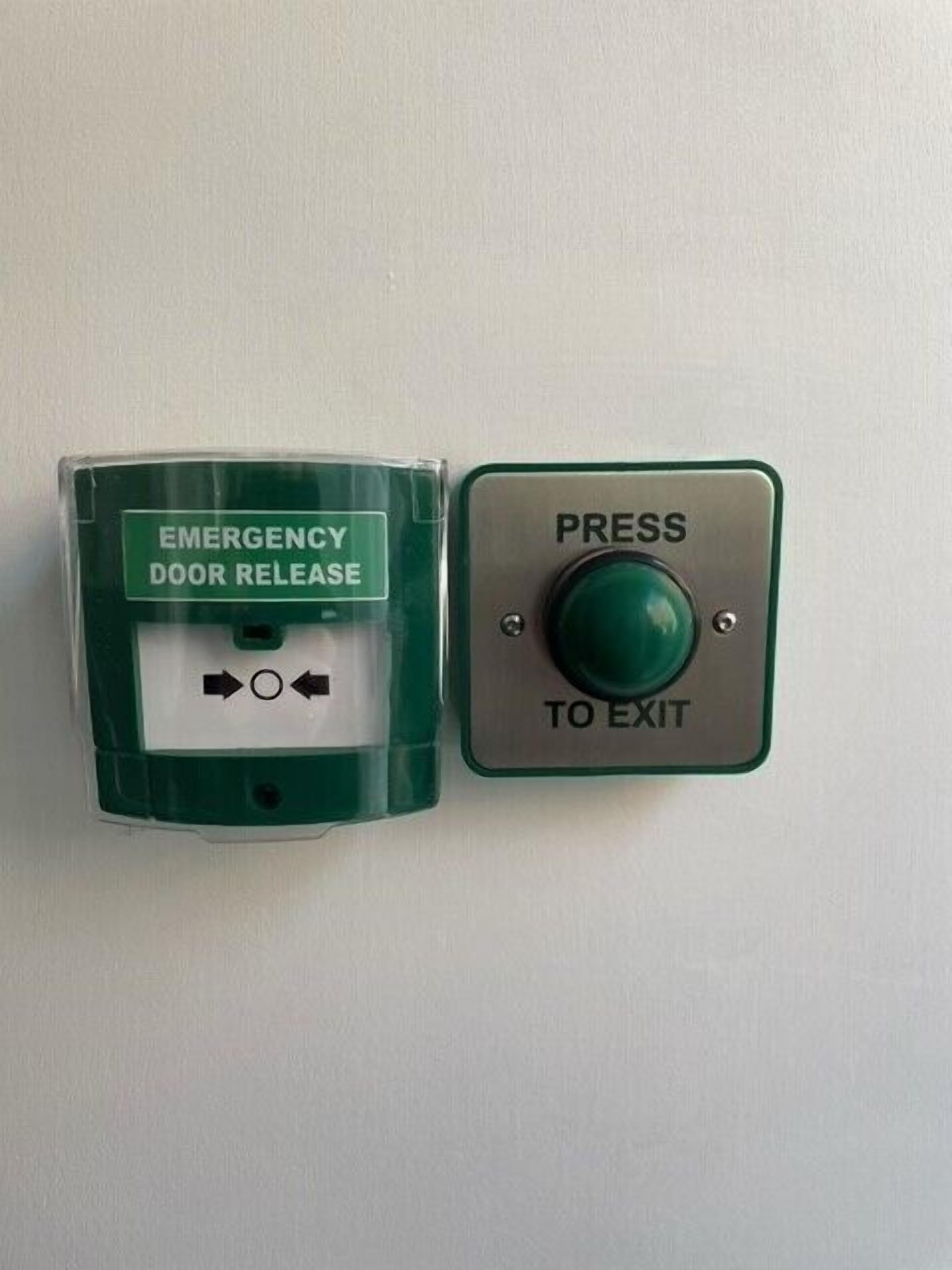 Un bouton de déverrouillage de la porte de secours et un bouton vert indiquant la sortie, tous deux situés sur un mur.