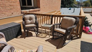 A wooden deck with wicker furniture, including two chairs and a small table. - Charming 2-bedroom apartment with AC, WIFI, Security Cameras at entrances. (Windsor)