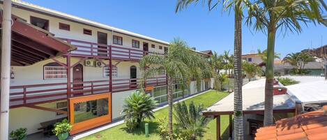 A multi-story building with a balcony, a well-maintained lawn, and several palm trees.