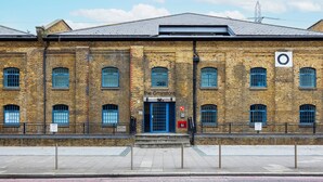 A brick building with a blue door and windows, labeled "The Grainstore." - Grain Store One Bed Luxury Property  (London)