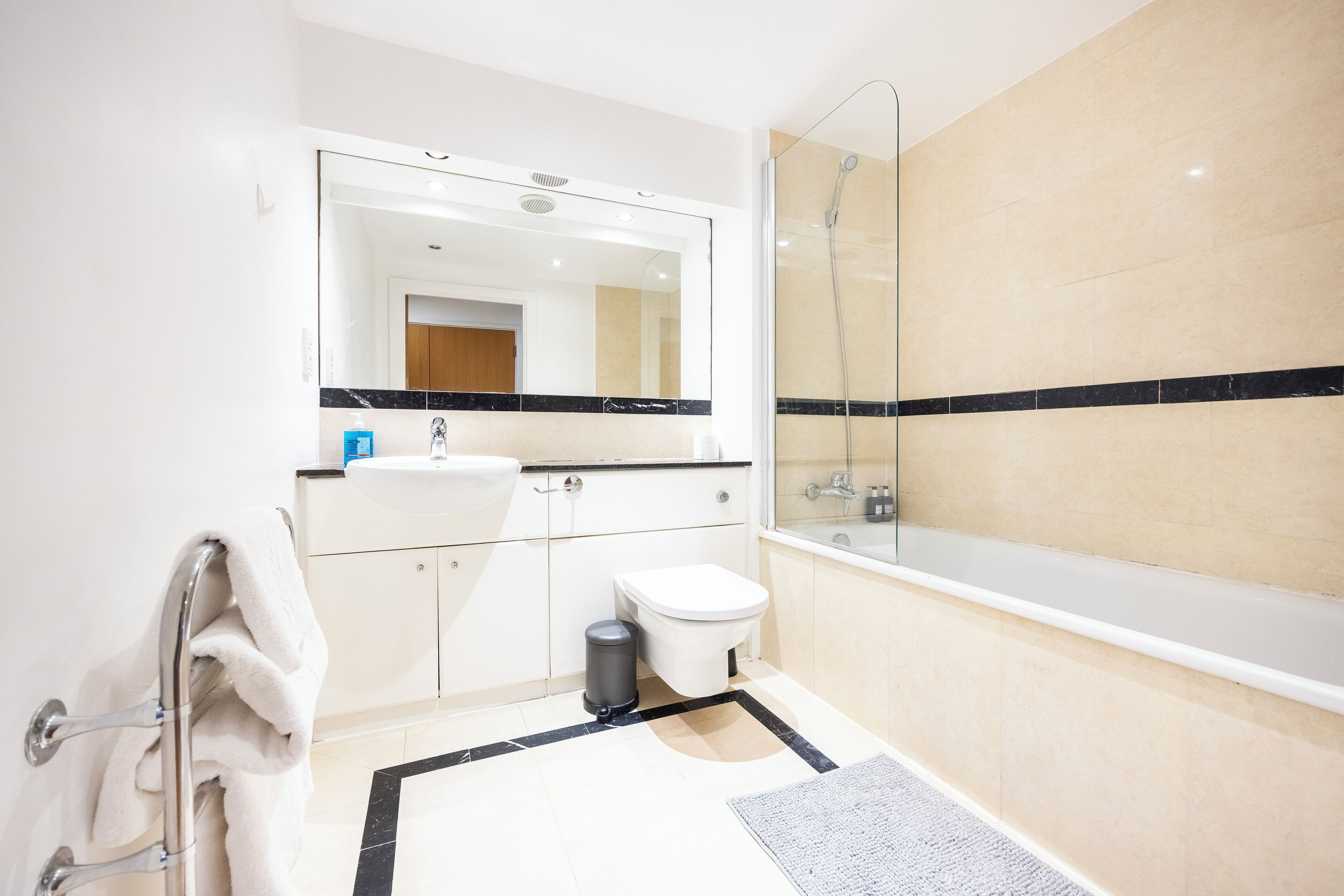 A modern bathroom with a glass-enclosed shower, a white sink, and a large mirror.