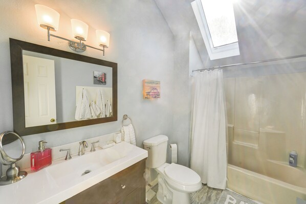 A bathroom with a large mirror, a white sink, a toilet, and a shower area. - 2 Mi to Boardwalk: Home w/ Deck in Bethany Beach! (Bethany Beach)