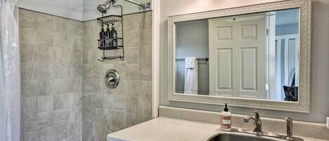 A bathroom with a shower, a sink, a mirror, and a towel rack.
