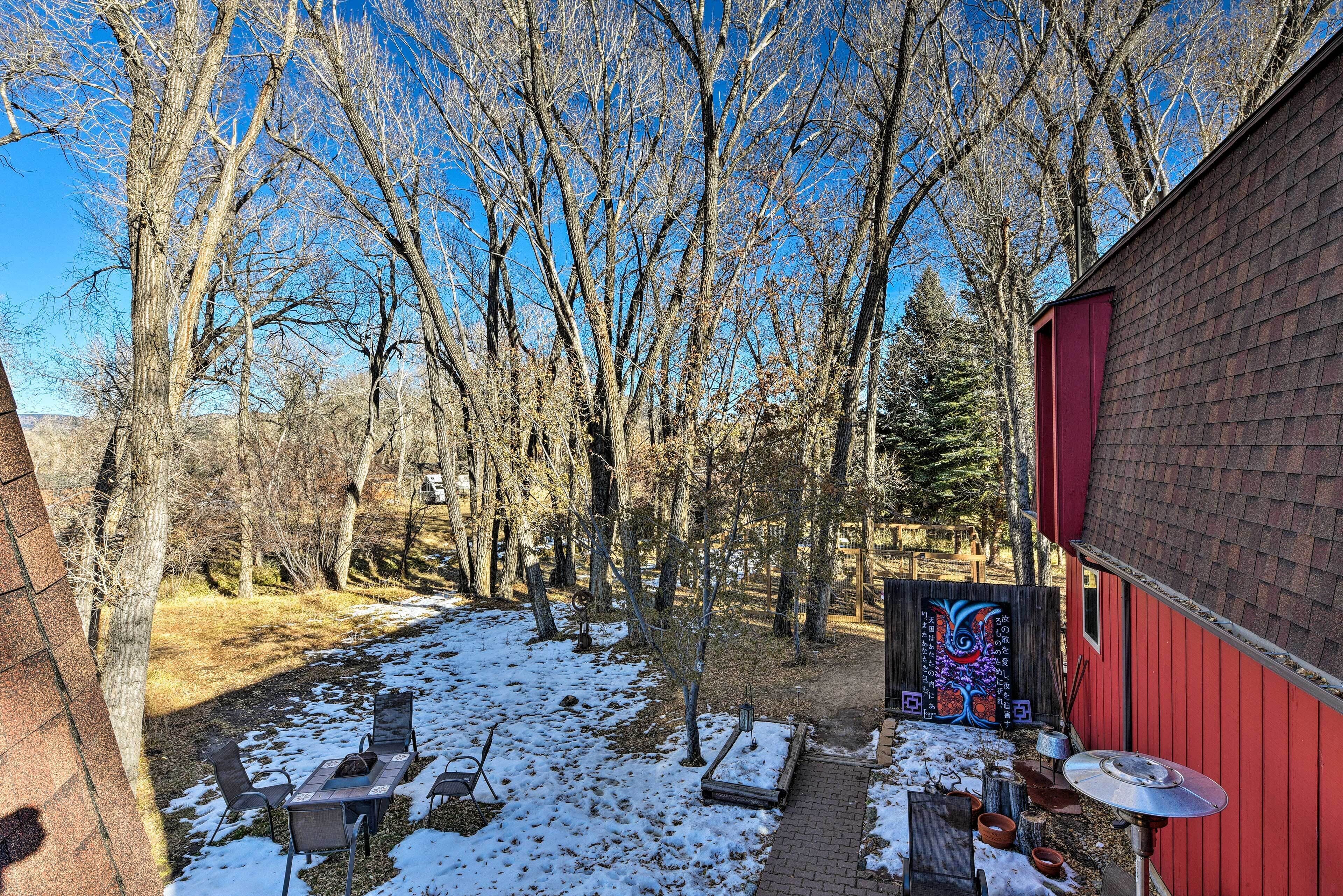 Un cortile con un capanno rosso, un muro in mattoni e terreno ricoperto di neve.