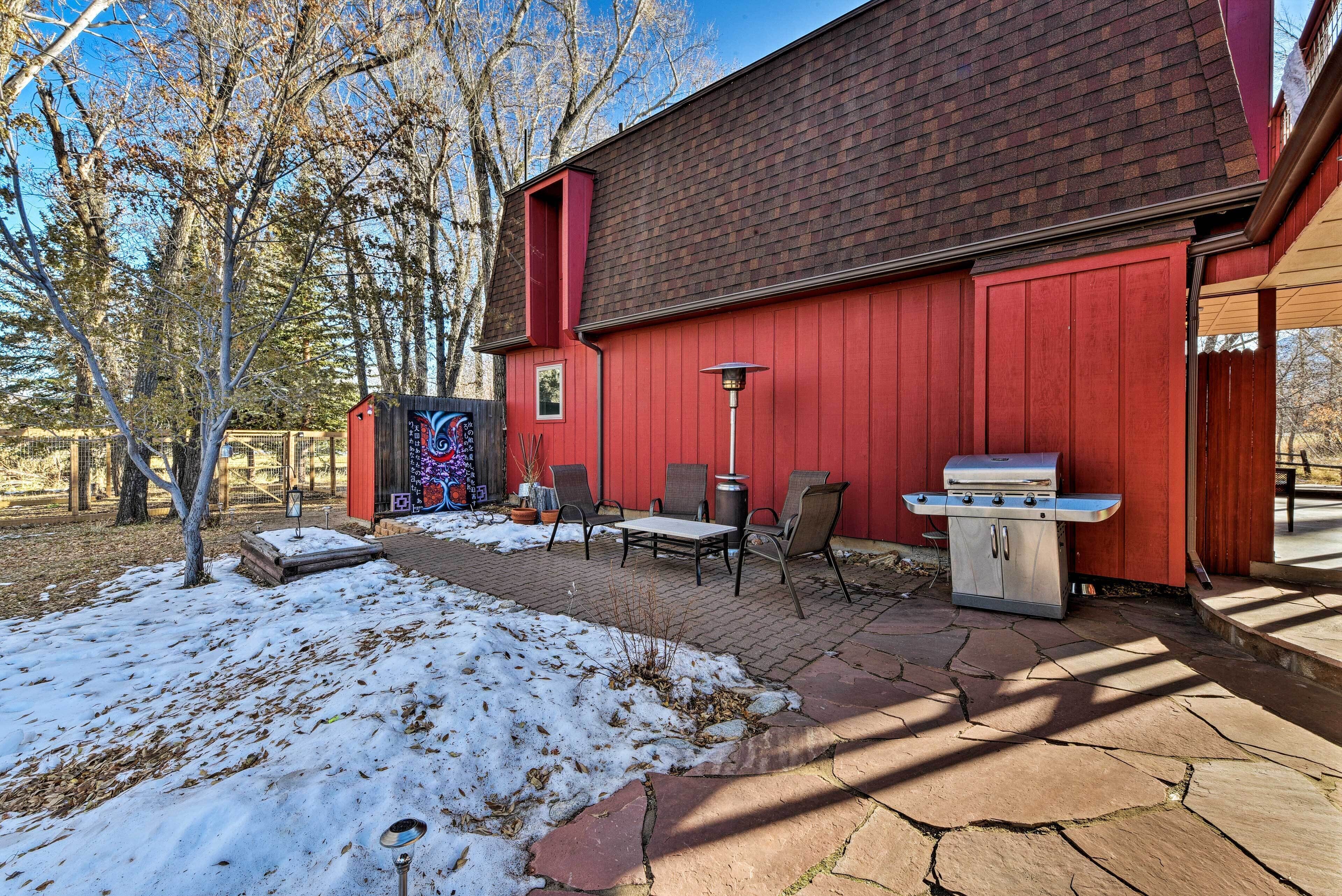 A red building with a brick roof, outdoor seating, and a barbecue grill.