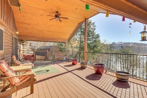 Une terrasse en bois avec des sièges d’extérieur, un ventilateur de plafond et des plantes en pot.