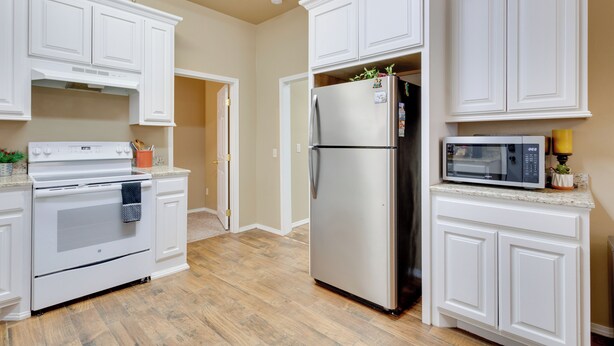 Una cocina con armarios blancos, un refrigerador de acero inoxidable, un microondas y un horno.