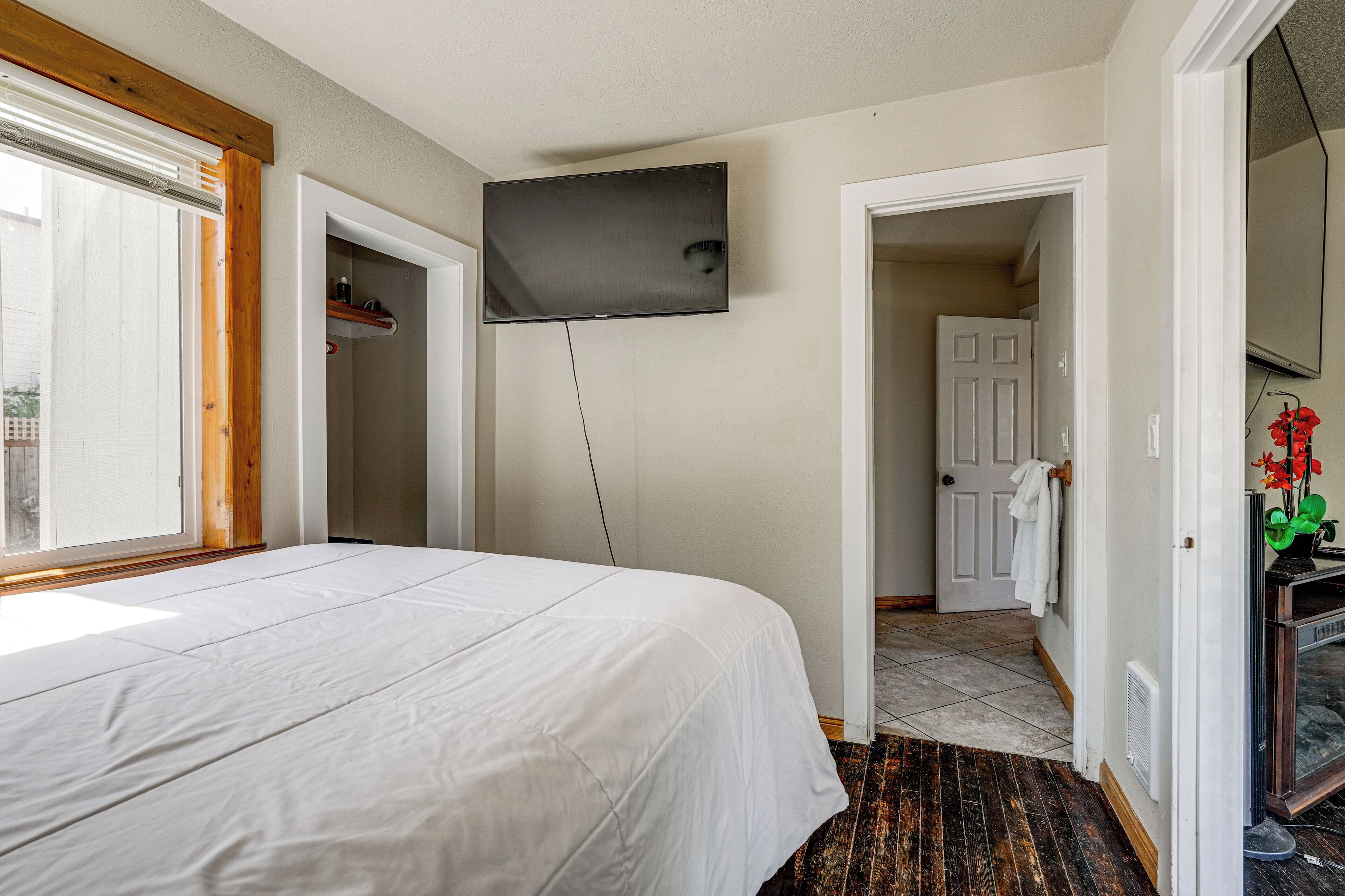 Een slaapkamer met een bed, een aan de muur bevestigde televisie en een deur naar een badkamer.