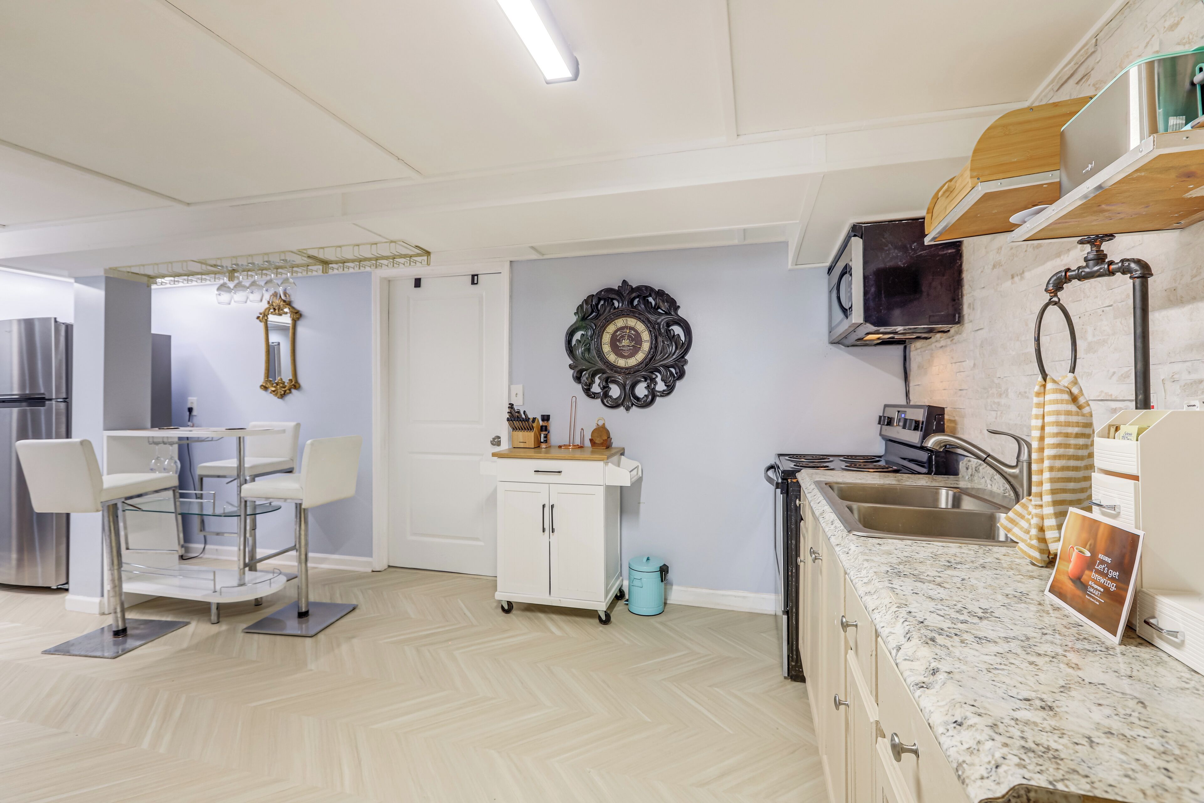 Una cucina moderna con un piano di lavoro in marmo, un lavandino e un'area pranzo con un tavolo e sedie bianche.