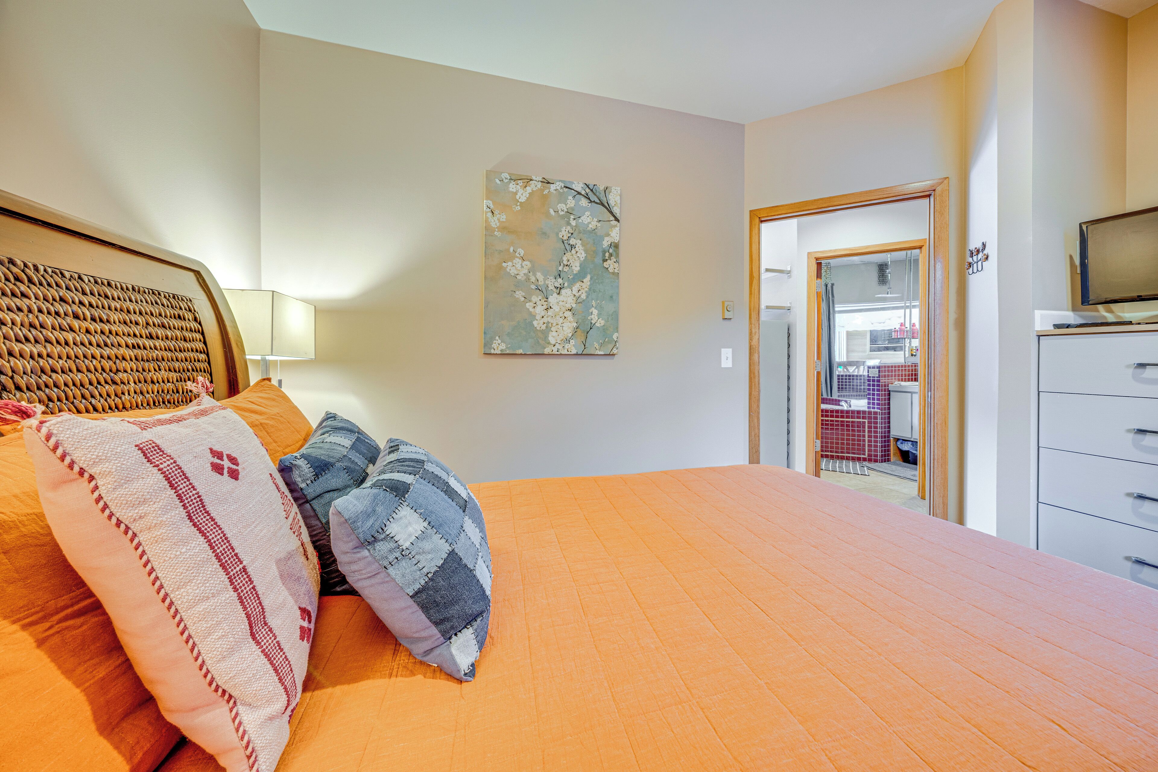 A bedroom with a large bed, a wooden headboard, and a painting on the wall.