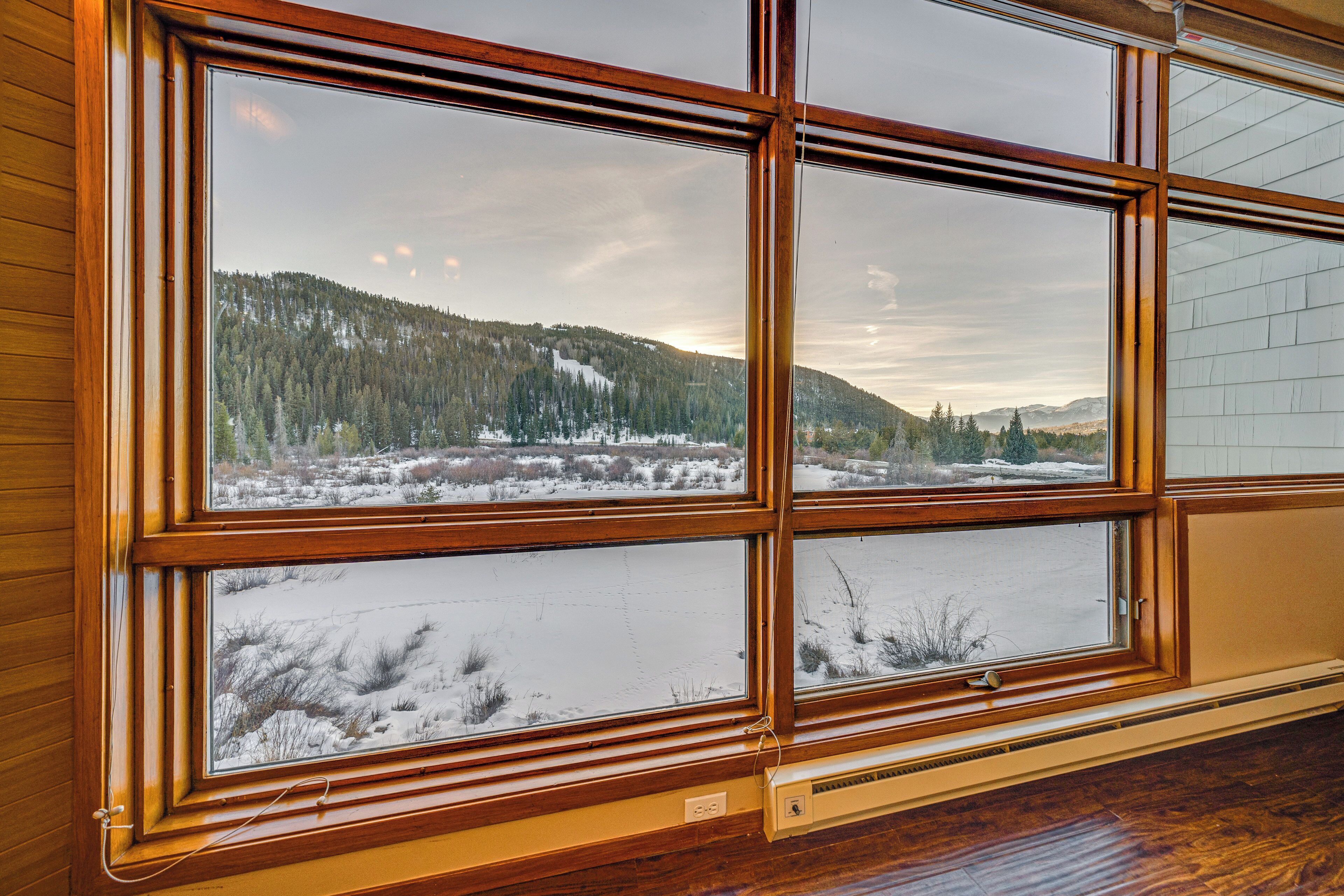 Una habitación con amplios ventanales que ofrecen vistas a un paisaje nevado y colinas boscosas.