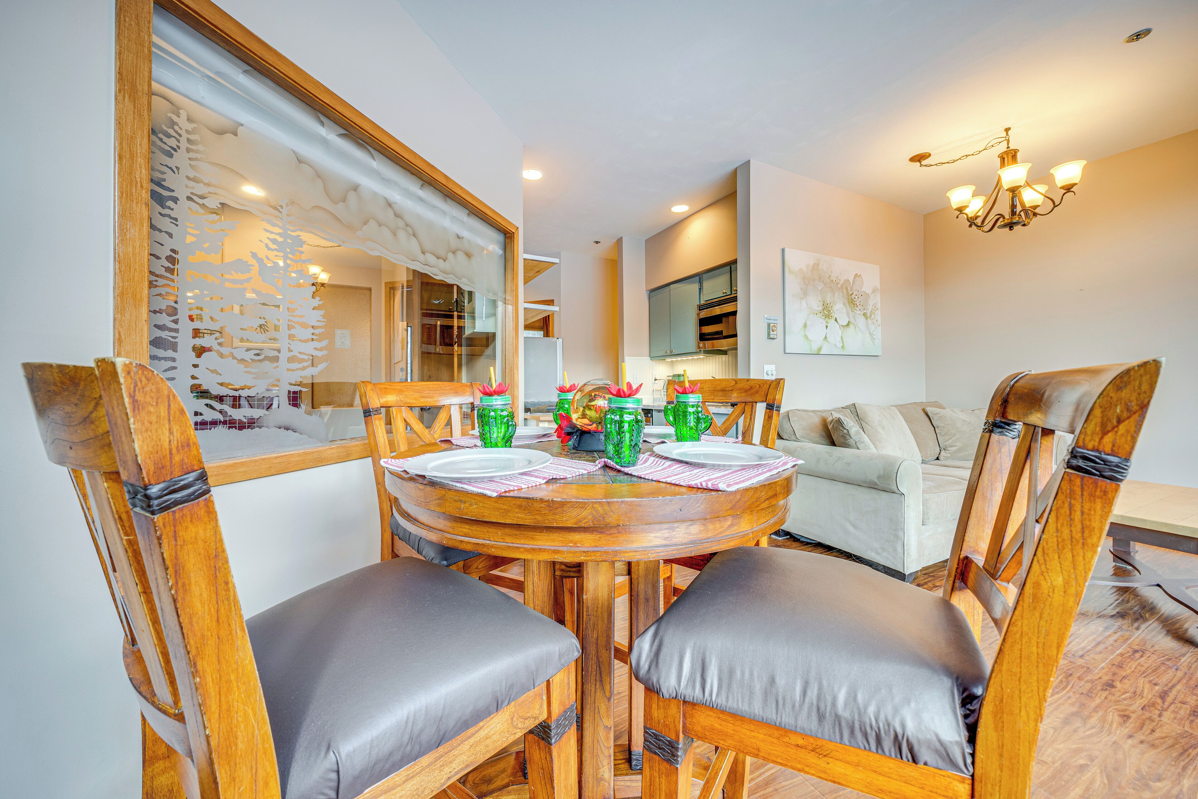 A dining area with a round wooden table, four chairs, and a mirror on the wall.