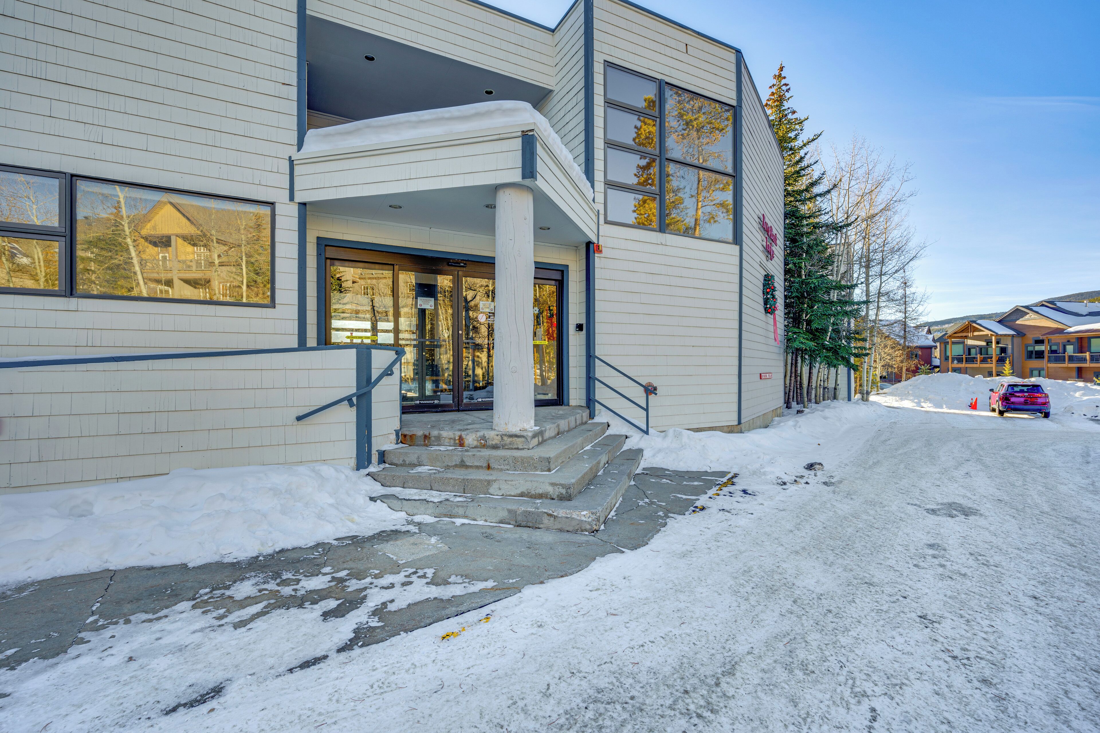 A building with a covered entrance, steps leading up to the door, and a snow-covered ground.