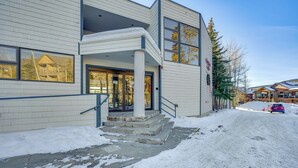 Un edificio con vestíbulo cubierto y escalones que conducen a la puerta, sobre un terreno cubierto de nieve.