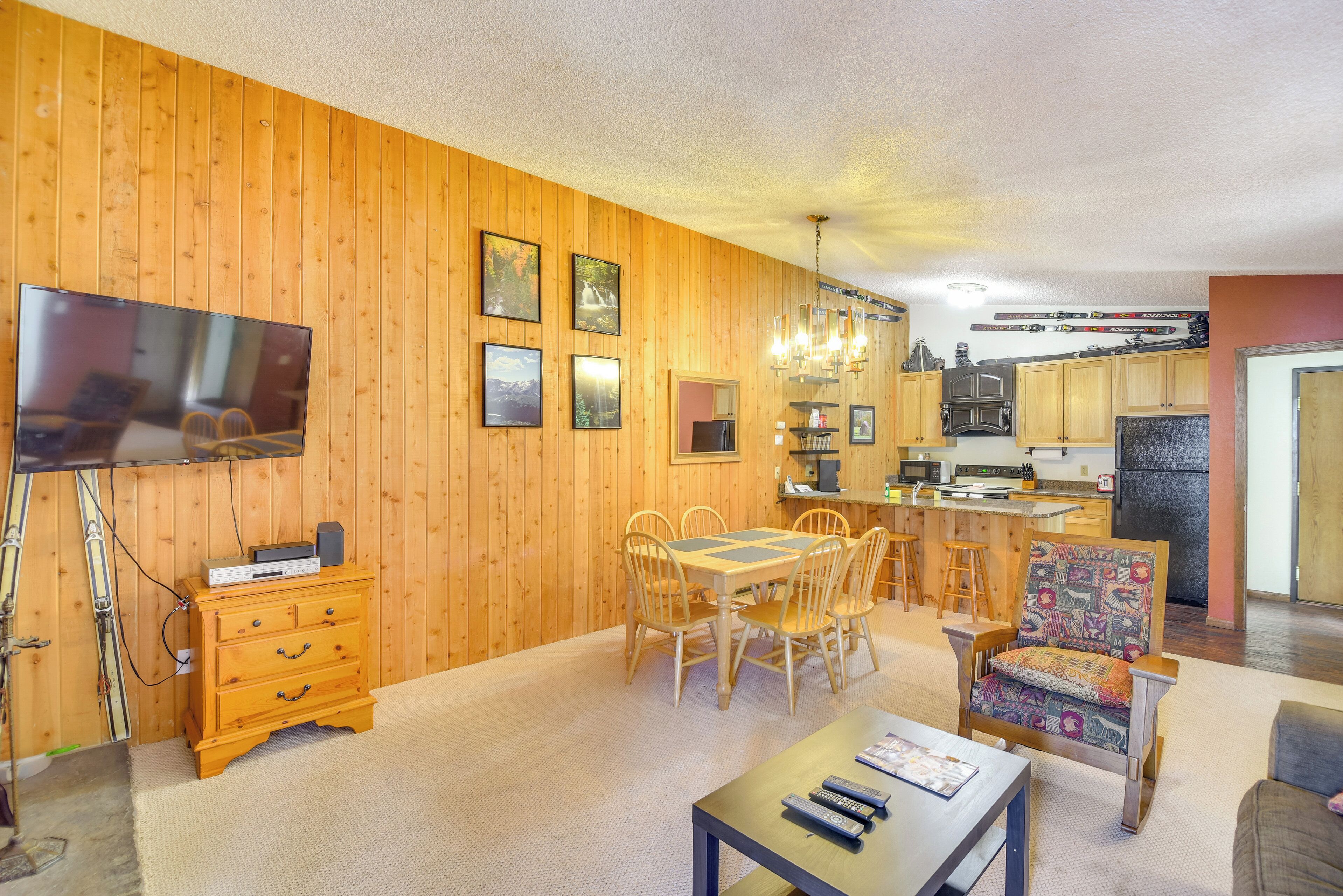 A cozy living room with wooden walls, a dining table, and a TV.