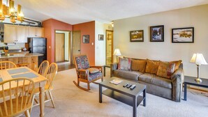 A living room with a sofa, coffee table, and chairs. There is a kitchen area with cabinets and a refrigerator. - Pool + Hot Tub Access: Condo in Winter Park! (Winter Park)