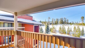 A balcony with a view of a snowy landscape and a building with red and yellow exterior walls. - Pool + Hot Tub Access: Condo in Winter Park! (Winter Park)