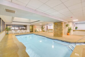 Ein Hallenbad mit Liegestühlen und einer Steinwand.
