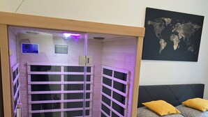 A room with a wooden sauna, a bed with patterned pillows, and a world map on the wall. - WohnTraum zur alten Post, old town, sauna (Meißen)