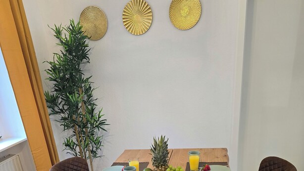 A wooden dining table with a baguette, fruit, and juice glasses. - WohnTraum zur alten Post, old town, sauna (Meißen)